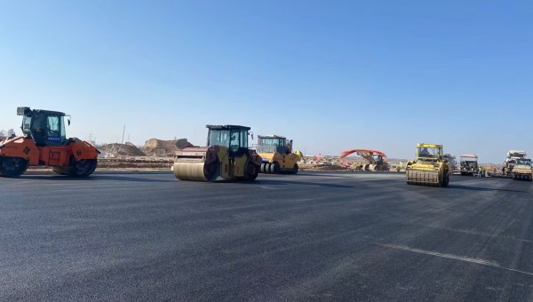 近日，在西部市政建设集团兰州新区城市矿产与表面处理产业园区（二期）周边基础设施项目—园区西路南延段（纬五十路至纬二十八路）项目现场，随着一辆辆运料车平稳驶入，摊铺机将滚烫的沥青混合料均匀铺开，标志着项